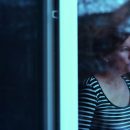 Depressed woman standing by the window and looking outside
