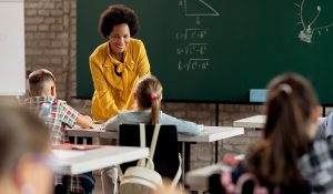 Happy black elementary school teacher taking to her students in