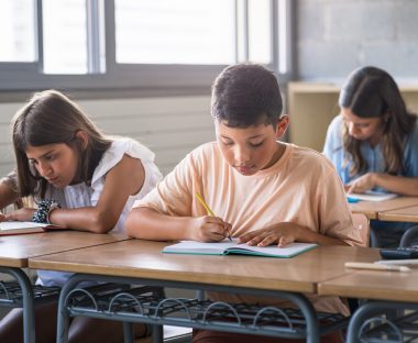 Hispanic,Primary,School,Boy,And,Girls,Writing,Test,At,Desk