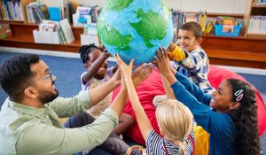 Group,Of,Multiethnic,Children,With,Male,Teacher,Holding,Model,Of