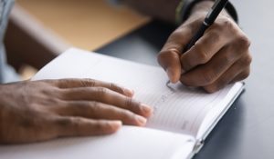 African,Man,Sit,At,Desk,Hold,Pen,Keeps,Startup,Business