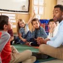 Elementary,School,Kids,And,Teacher,Sit,Cross,Legged,On,Floor