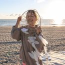 Little girl with a dream catcher on the seashore at sunset.