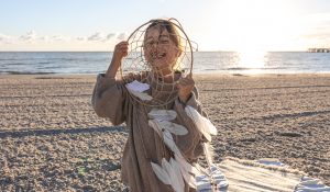 Little girl with a dream catcher on the seashore at sunset.