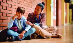 African,American,Teacher,Talking,To,Sad,Elementary,Student,In,A