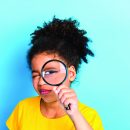 Young,Girl,With,Curly,Hair,Exploring,With,A,Magnifying,Glass