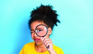 Young,Girl,With,Curly,Hair,Exploring,With,A,Magnifying,Glass
