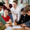 Involved,Teenage,Students,Discussing,The,Task,At,Table,While,Teacher