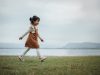 Happy,Toddle,Girl,Walking,On,A,Grass,Field,Near,The