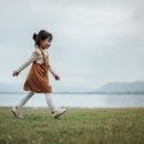 Happy,Toddle,Girl,Walking,On,A,Grass,Field,Near,The