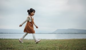 Happy,Toddle,Girl,Walking,On,A,Grass,Field,Near,The