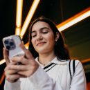 Woman,Smiling,While,Reading,Something,On,Smartphone,Screen,,Emphasizing,Satisfaction