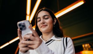 Woman,Smiling,While,Reading,Something,On,Smartphone,Screen,,Emphasizing,Satisfaction