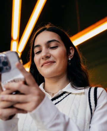 Woman,Smiling,While,Reading,Something,On,Smartphone,Screen,,Emphasizing,Satisfaction