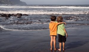 Two,Young,Boys,,Brothers,Or,Friends,,Stand,Hugging,On,Beach