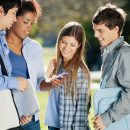 Young,Female,Student,Showing,Mobilephone,To,Classmates,In,College,Campus