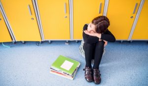 Portrait,Of,Schoolgirl,Sitting,By,Lockers.,Student,Girl,With,Bag