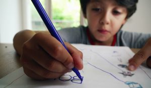 Young,Boy,Focusing,On,Tracing,Words,On,A,Worksheet,,Developing