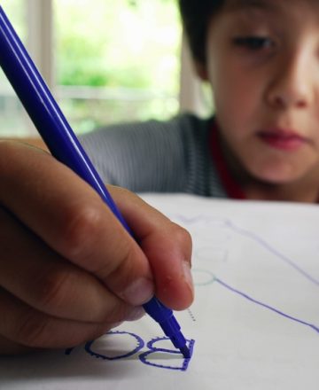 Young,Boy,Focusing,On,Tracing,Words,On,A,Worksheet,,Developing
