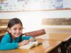 Child,Female,Student,Sitting,In,Classroom,At,Desk,Reading,Book,