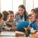 Happy,Female,Teacher,Assisting,Students,In,Classroom,,Educating,Children,,Learning
