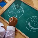 Child,Pointing,At,Chalkboard,With,Emotional,Faces,During,Psychology,Therapy