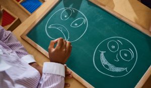 Child,Pointing,At,Chalkboard,With,Emotional,Faces,During,Psychology,Therapy